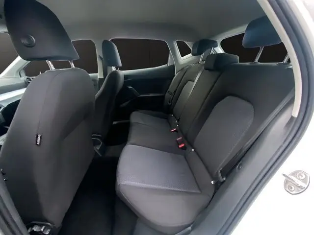 Vue intérieure du siège arrière côté droit d'une SEAT IBIZA blanc candy 2023, tissu gris et ceintures visibles.