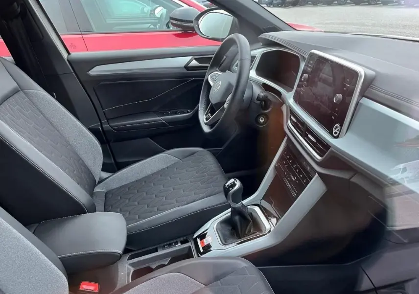 Intérieur du Volkswagen T-Roc 2.0 TDI 116CH Life Plus 2025, vue côté conducteur, sièges tissu gris et console centrale avec boîte manuelle.