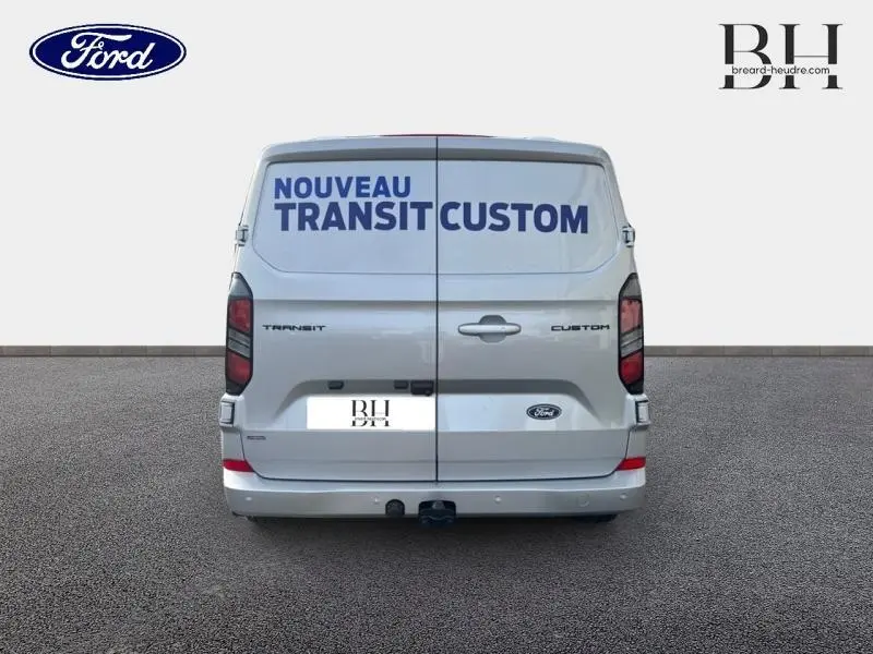 Vue arrière du Ford Transit Custom gris lunaire métallisé avec double portes arrière fermées et crochet d'attelage visible.