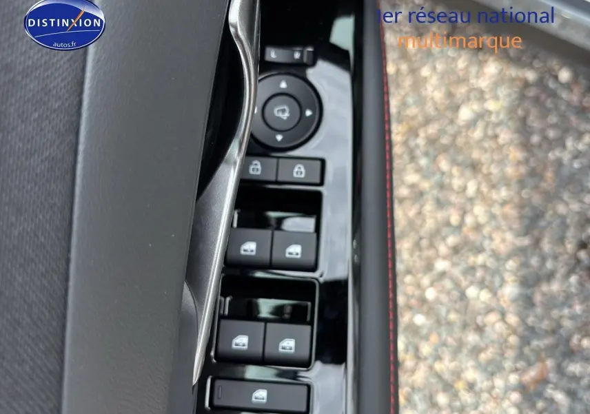 Gros plan sur la commande des vitres électriques côté conducteur du Hyundai Tucson gris Shadow, avec surpiqûres rouges visibles.