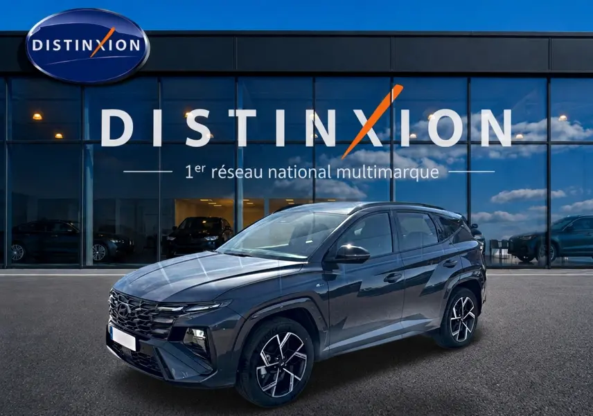 Hyundai Tucson 2026 gris ecotronique en 3/4 avant droit, avec calandre glossy black et jantes alliage 19 pouces.