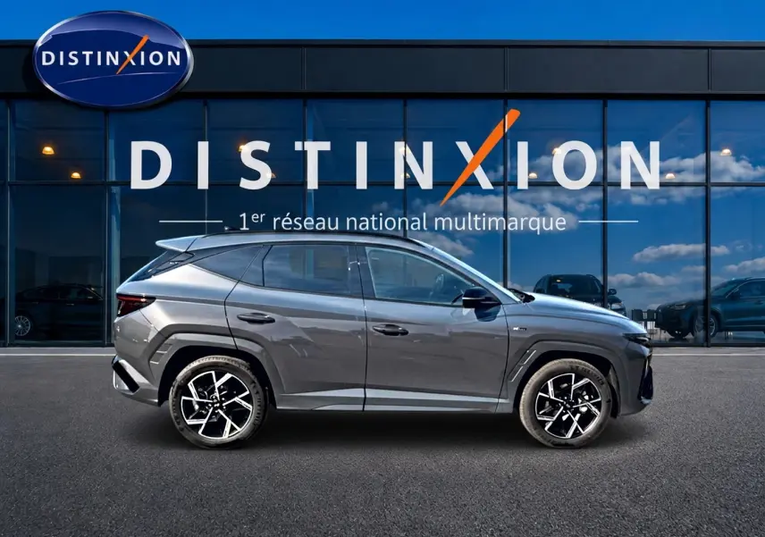 Hyundai Tucson 2026 gris écotronique en profil droit, avec jantes alliage 19 pouces et barres de toit visibles.