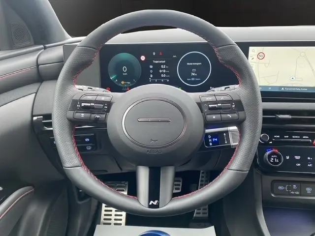 Vue centrée sur le volant cuir N Line avec coutures rouges du Hyundai Tucson gris foncé, tableau de bord digital et écran tactile visible.