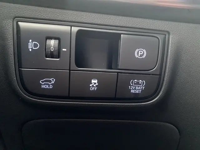 Gros plan sur les commandes intérieures du Hyundai Tucson 1.6 Hybrid 239 N Line, boutons de frein à main électrique et assistance.