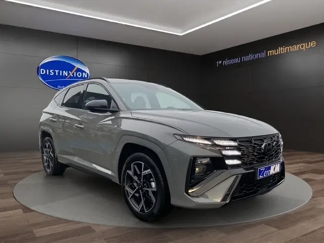 Hyundai Tucson 1.6 Hybrid gris foncé en 3/4 avant droit, avec calandre distinctive et jantes alliage noires.