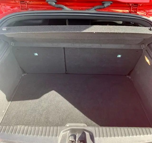 Coffre ouvert vu de l'arrière d'une Renault Clio V rouge 2021, montrant un espace de chargement propre et vide.