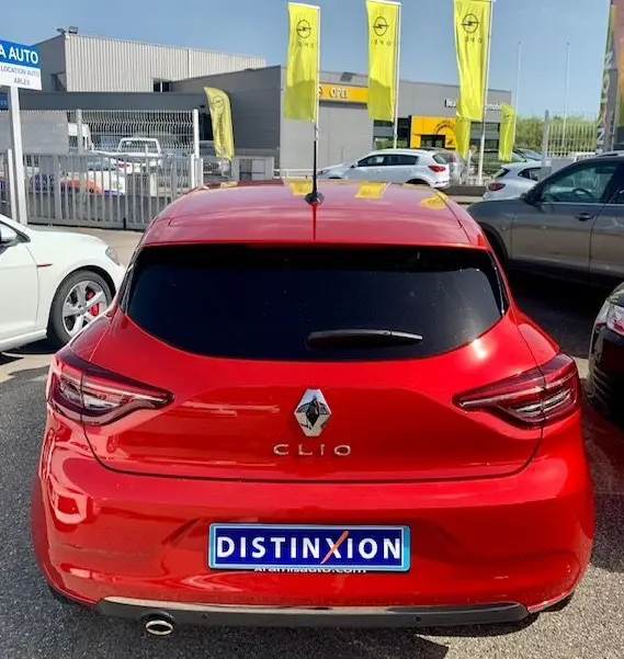 Vue arrière d'une Renault Clio V rouge 2021 avec vitres teintées et plaque d'immatriculation Distinxion visible.