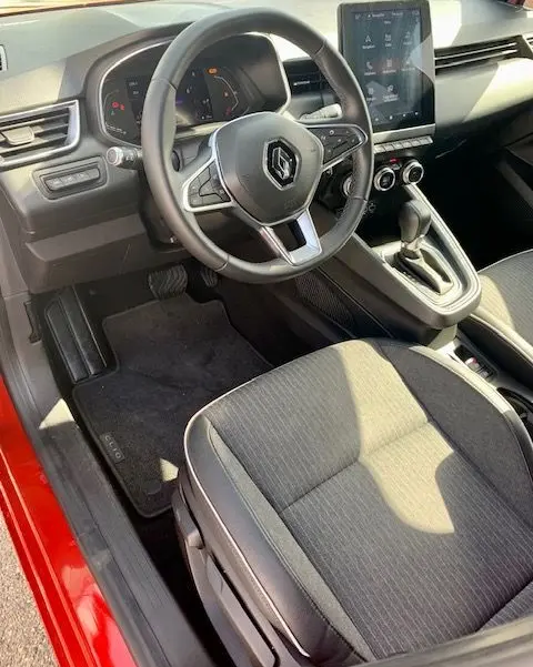Intérieur de la Renault Clio V rouge, vue côté conducteur, volant multifonction et écran tactile central visible