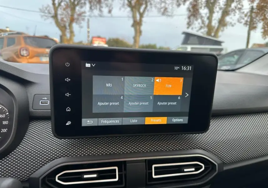 Écran tactile central de la Dacia Sandero TCe 90 blanc 2024, vue intérieure du tableau de bord avec radio FM affichée.