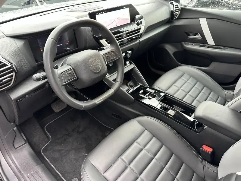 Vue intérieure côté conducteur de la Citroën C4 X 2025, avec tableau de bord moderne et sièges cuir gris Mercury.