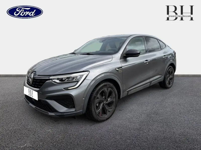 Renault Arkana gris métallisé en vue 3/4 avant droit, avec jantes noires et calandre distinctive RS Line.