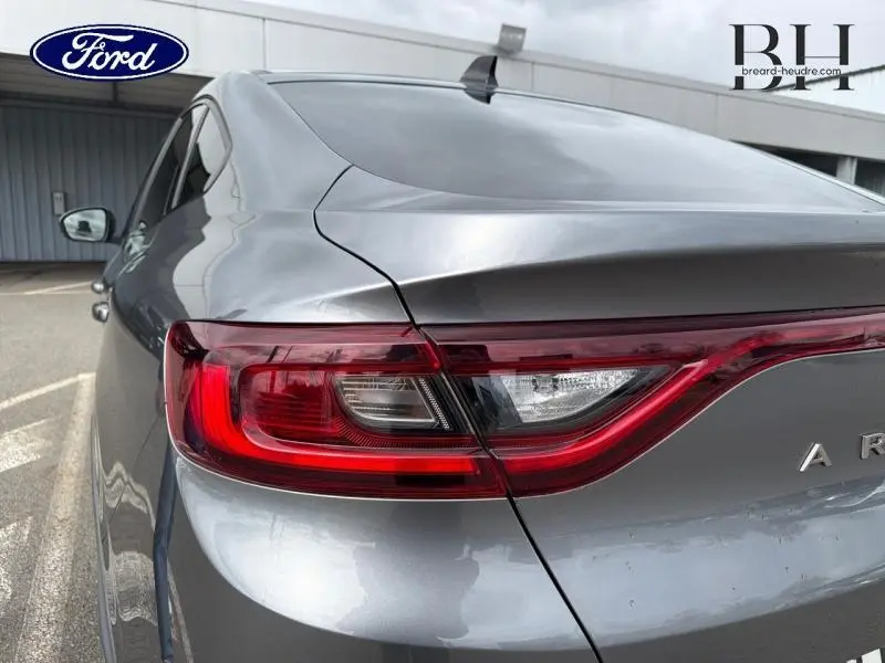 Gros plan sur le feu arrière droit du Renault Arkana gris métallisé, soulignant la ligne fluide du hayon arrière.