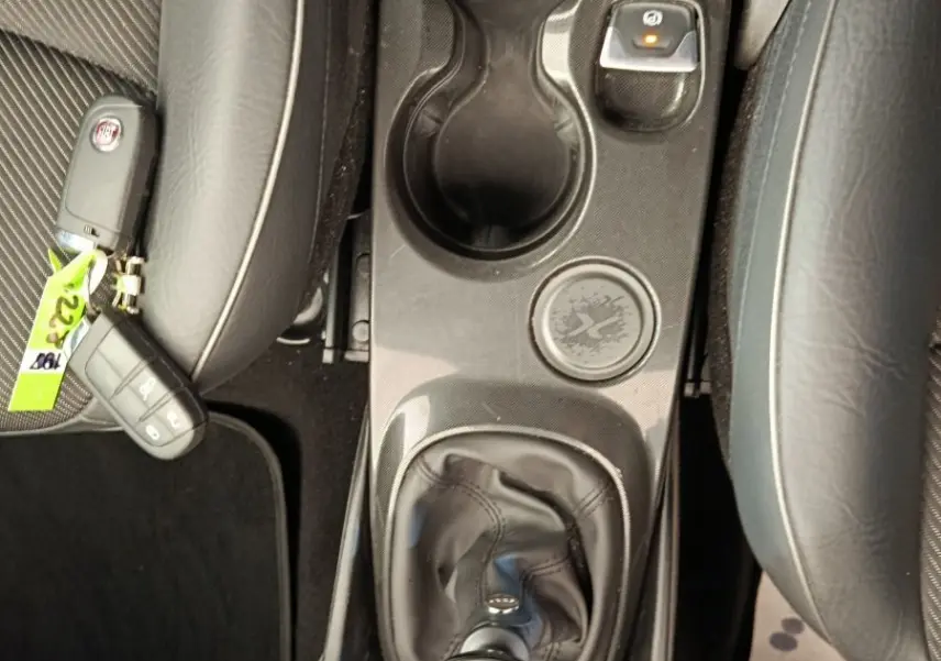 Vue plongeante sur la console centrale noire d'une Fiat 500X 2020 avec levier de vitesse manuel et porte-gobelets.