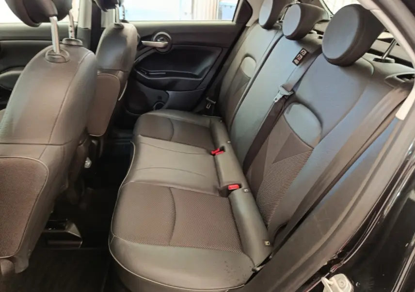 Vue intérieure côté droit des sièges arrière noirs en cuir et tissu d'une Fiat 500X 2020, porte ouverte.