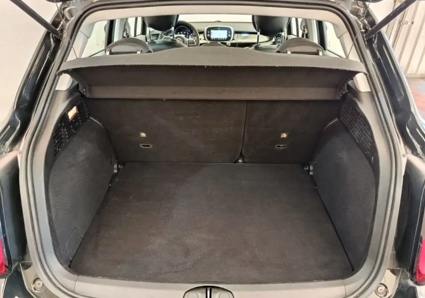 Coffre ouvert vu de l'arrière d'une FIAT 500X noire avec banquette arrière et tableau de bord visibles.