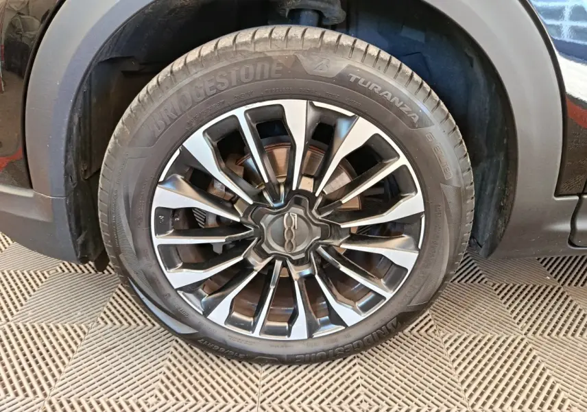 Gros plan sur la roue avant droite avec jante alliage bicolore du FIAT 500X blanc Cross 2020.