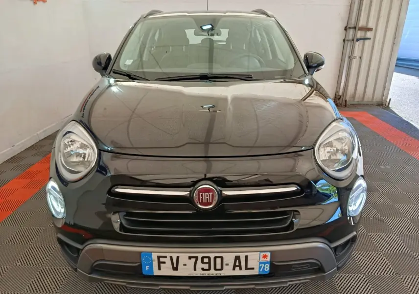 Vue avant d'un FIAT 500X noir avec phares ronds allumés et calandre chromée dans un garage.