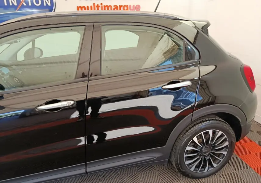 Vue latérale droite d'une FIAT 500X noire avec jantes alliage et poignées de porte chromées.