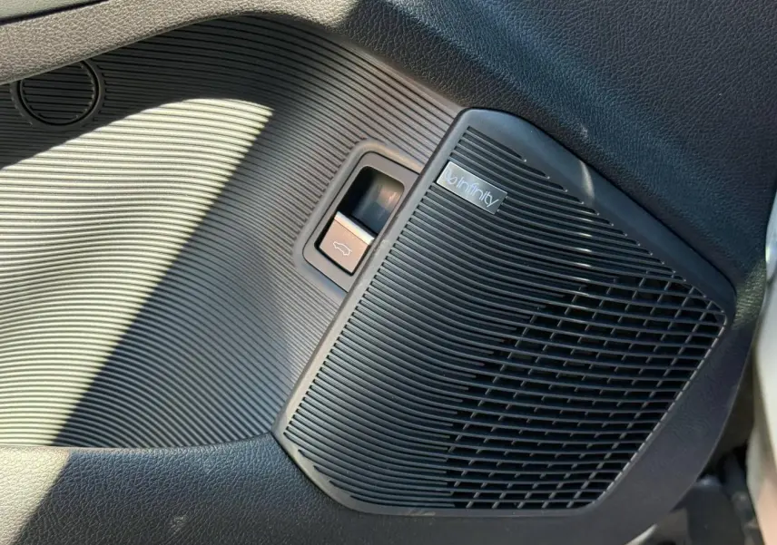Gros plan sur le haut-parleur Infinity noir et bouton d'ouverture du coffre côté conducteur du BYD SEAL U 1.5 DM-i 218ch Boost.