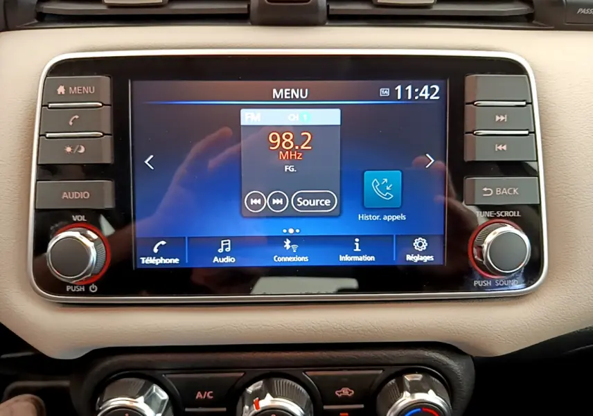 Écran tactile central de la Nissan Micra IG-T 92 Acenta 2022, affichant la radio FM, entouré de commandes audio et climatisation beige.