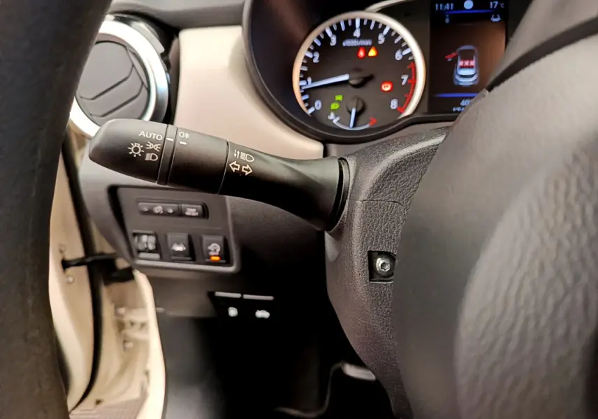 Gros plan sur le volant et le tableau de bord de la Nissan Micra blanche, avec commandes et affichages visibles.