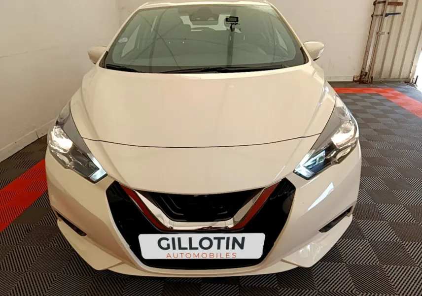 Vue de face d'une Nissan Micra blanche 2022 avec phares allumés et calandre noire brillante.