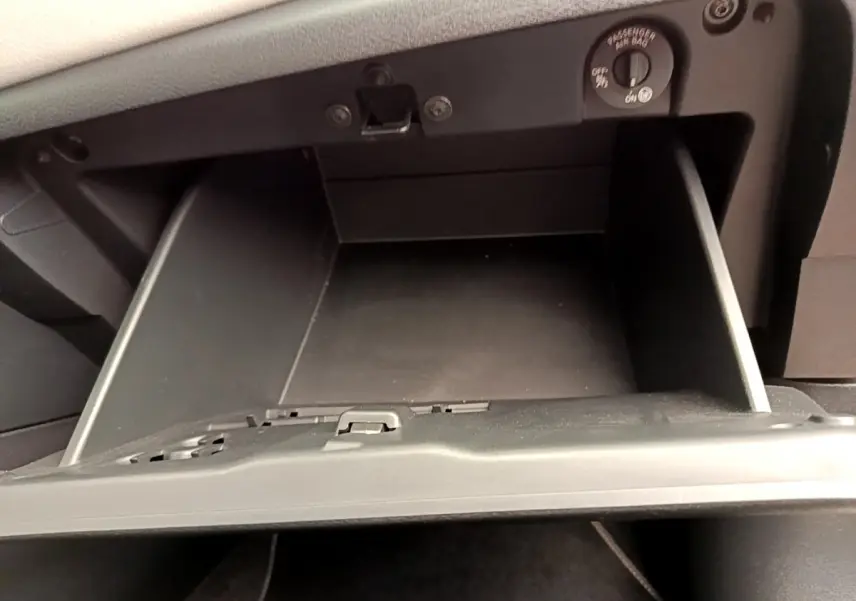 Gros plan sur la boîte à gants noire ouverte de la Nissan Micra IG-T 92 Acenta blanche, intérieur visible.