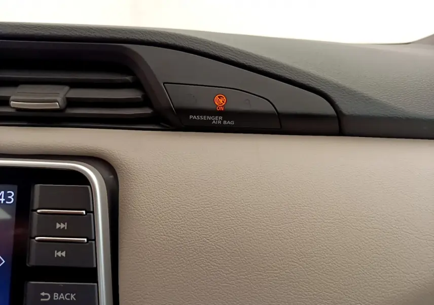 Détail du tableau de bord beige de Nissan Micra 2022 avec témoin airbag passager allumé en orange