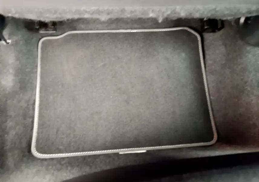 Vue rapprochée du coffre intérieur noir de la Nissan Micra IG-T 92 Acenta blanche, soulignant la moquette et le tapis.