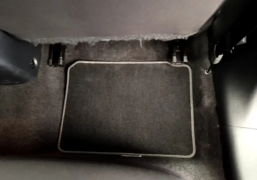 Tapis de sol noir avec surpiqûres blanches dans l'habitacle d'une Nissan Micra IG-T 92 Acenta blanche, vue intérieure au sol côté passager.