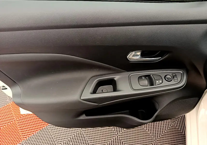 Gros plan sur la porte côté conducteur noire de la Nissan Micra IG-T 92 Acenta blanche avec commandes électriques des vitres.