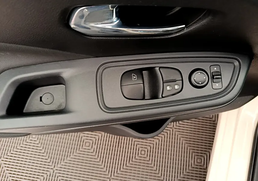Gros plan sur la commande des vitres et rétroviseurs côté conducteur d'une Nissan Micra blanche 2022.