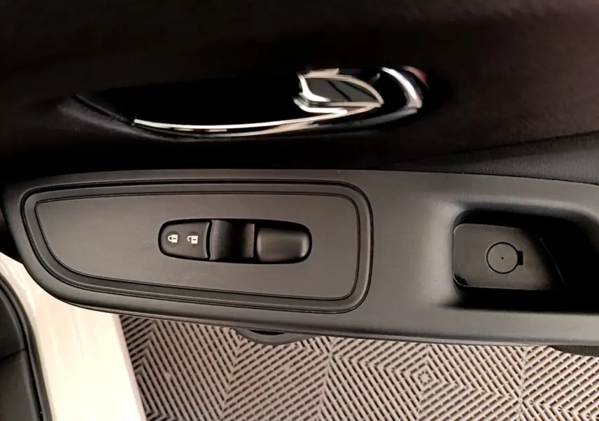 Poignée intérieure noire côté conducteur de la Nissan Micra IG-T 92 Acenta blanche, avec commandes de verrouillage.