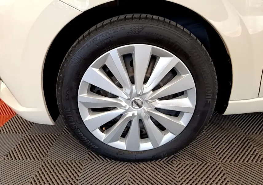 Gros plan sur la roue avant droite d'une Nissan Micra blanche, mettant en valeur la jante et le pneu Bridgestone.