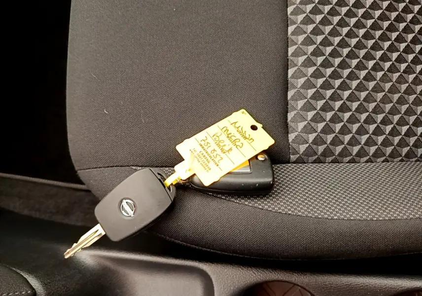 Clé de voiture Nissan posée sur un siège avant noir avec tissu à motifs géométriques à l'intérieur d'une Micra blanche 2022.