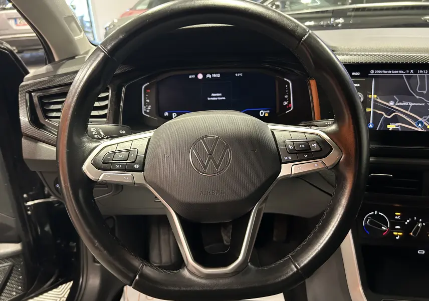 Vue rapprochée du volant en cuir noir de la Volkswagen Polo 2022 avec affichage numérique et écran GPS tactile.