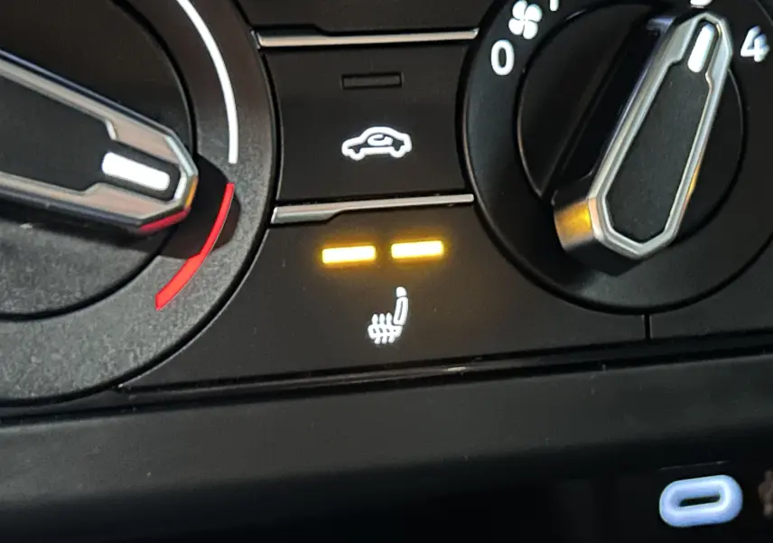 Gros plan sur le tableau de bord noir de la Volkswagen Polo 2022, voyant sièges chauffants allumé en jaune.