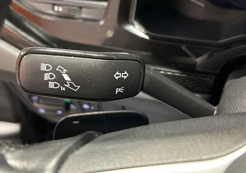 Gros plan sur la manette de clignotants noire dans l’habitacle d’une Volkswagen Polo noire de 2022.