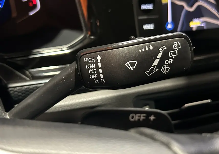 Gros plan sur la commande d’essuie-glace à droite du volant dans l’habitacle noir d’une Volkswagen Polo 2022.
