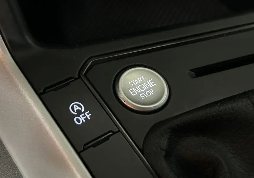 Gros plan sur le bouton Start Engine Stop et la commande d'arrêt du système auto start/stop dans l'habitacle noir d'une Volkswagen Polo.
