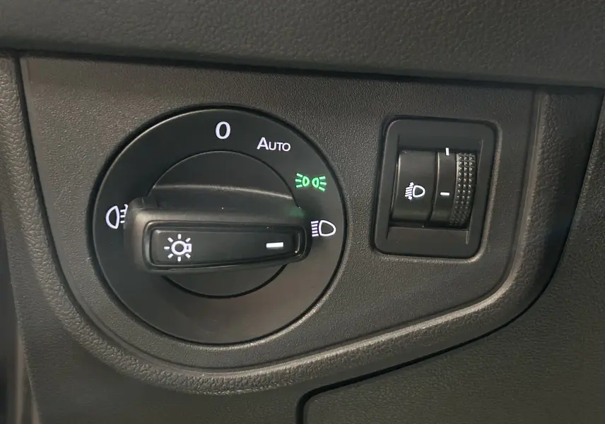 Gros plan sur le bouton de commande des phares et le réglage d’intensité lumineuse dans l’habitacle d’une Volkswagen Polo noire.