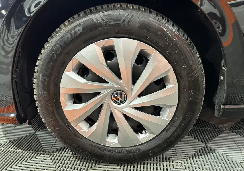 Gros plan sur la roue avant droite noire d’une Volkswagen Polo 2022 avec jante argentée et logo VW central.