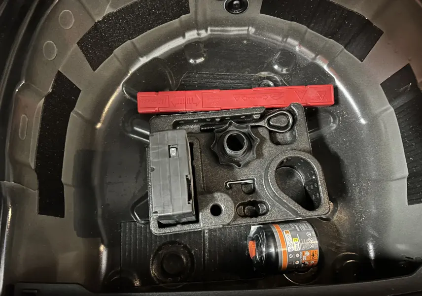Vue rapprochée de la trousse à outils et kit de réparation dans le coffre d'une Volkswagen Polo noire 2022.