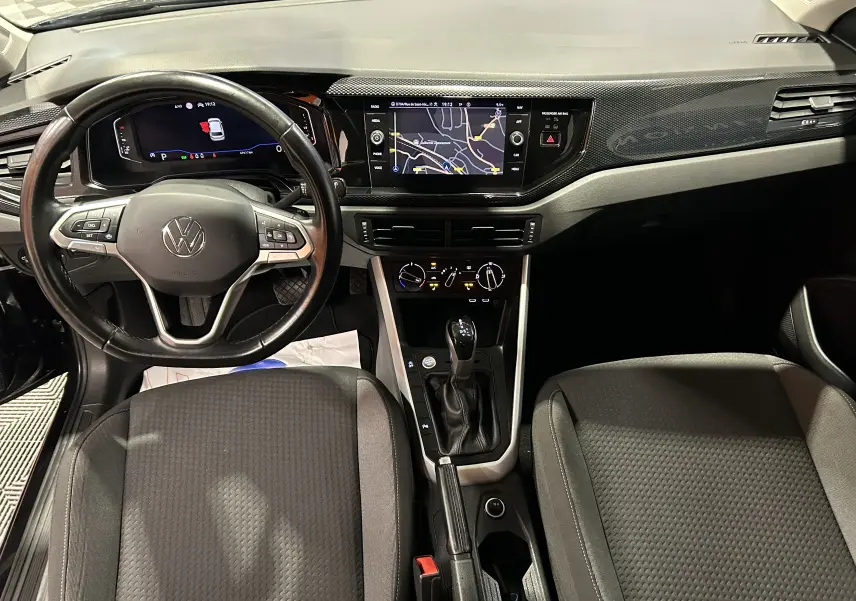 Vue intérieure avant de la Volkswagen Polo noire 2022, mettant en valeur le volant multifonction, l'écran tactile GPS et la console centrale.