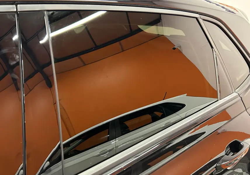 Reflet du côté droit d'une Volkswagen Polo noire 2022, mettant en valeur la porte arrière et la poignée sous un éclairage intérieur.