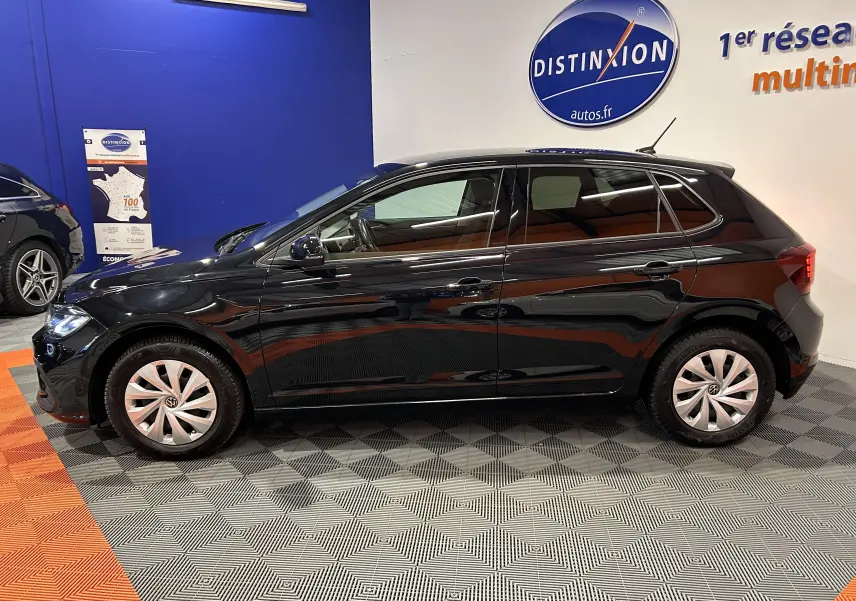 Profil droit d'une Volkswagen Polo noire 2022, avec jantes en alliage et vitres teintées, en intérieur showroom.