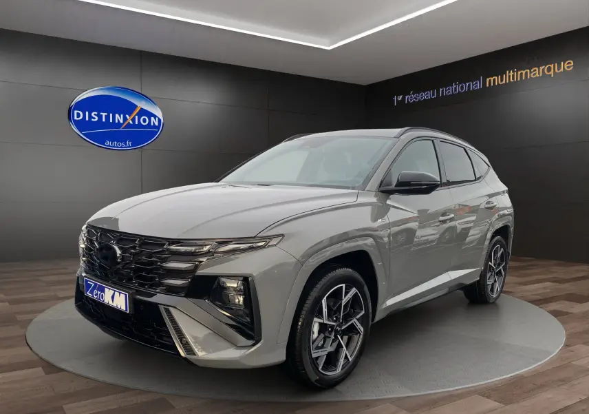 Hyundai Tucson 2026 gris Shadow en 3/4 avant droit, avec jantes alu 19 pouces et calandre noire distinctive.