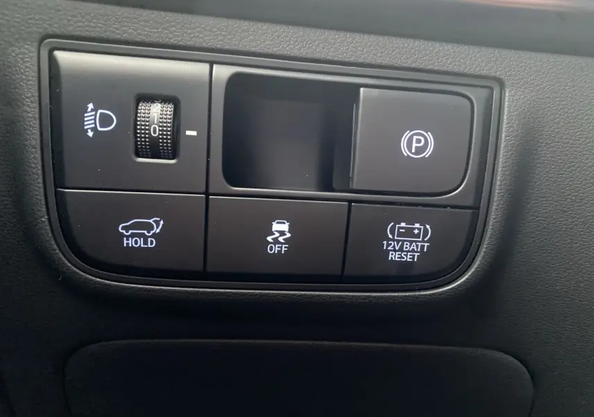 Gros plan sur les commandes noires du tableau de bord du Hyundai Tucson 2026, avec boutons d'assistance et réglage des phares.