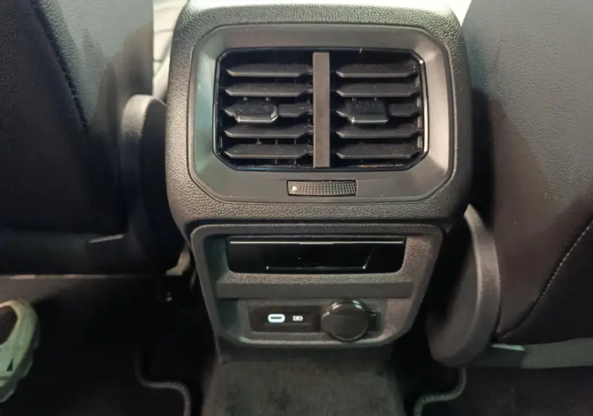 Vue rapprochée de la console arrière noire du Volkswagen Tiguan 2023 avec aérateurs et prises USB visibles.