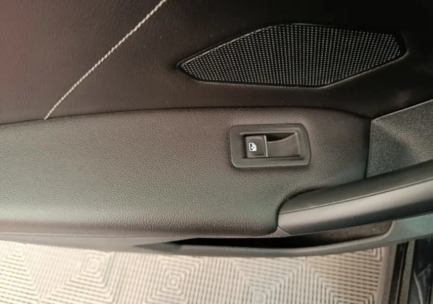 Détail de la porte intérieure côté conducteur du Volkswagen Tiguan noir, avec bouton de verrouillage et haut-parleur intégré.